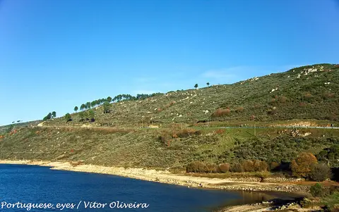 Albufeira da Barragem do Caldeirão com encosta verde e céu azul