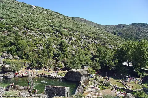 Praia fluvial de Loriga, com piscina natural entre rochas e encosta verde da serra ao fundo
