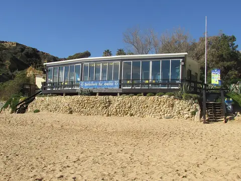 Restaurante Bar Aveiros sobre muro de pedra, visto da areia da Praia de Aveiros, Albufeira