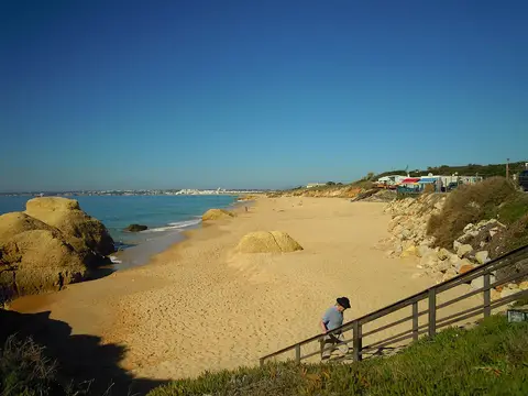 Praia da Galé com areal dourado, rochas e escadaria de acesso junto à falésia