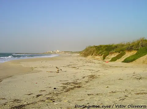Praia de areia deserta de São Pedro de Maceda com dunas cobertas de vegetação e mar calmo
