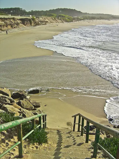Escadas de acesso ao areal da praia de Cortegaça, com ondas a rebentar e dunas ao fundo