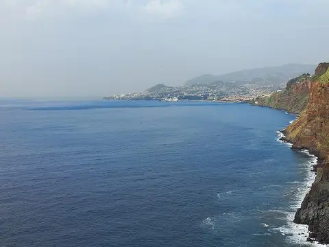 Vista da Ponta do Garajau sobre o mar e a costa em direção ao Funchal, com falésias à direita