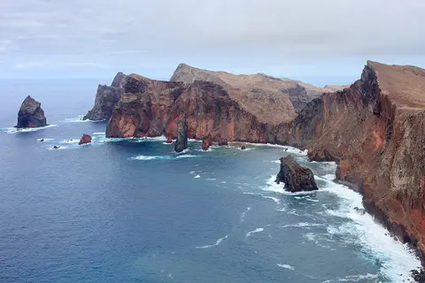 Vista da costa rochosa e falésias avermelhadas da Ponta de São Lourenço, na Madeira, sobre o mar azul