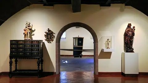 Sala do Museu da Quinta das Cruzes com contador, esculturas religiosas e palanquim ao fundo