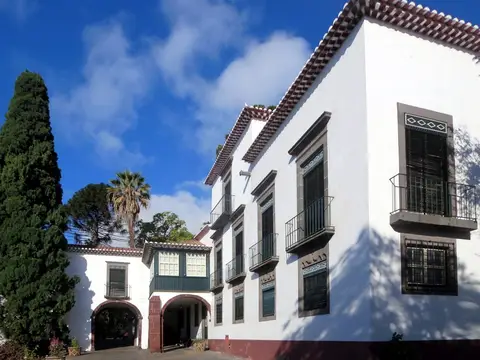 Fachada branca da casa senhorial do Museu da Quinta das Cruzes, no Funchal, com varandas e jardim