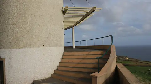Escadaria curva e pérgola do miradouro, com vista sobre o mar e campos ao fundo