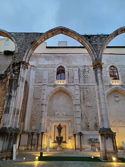 Arcos góticos e interior das ruínas do Convento do Carmo, em Lisboa, iluminados ao anoitecer