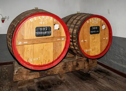 Duas pipas de vinho Madeira da Blandy's, com aros vermelhos e tabuletas, numa adega de chão de madeira
