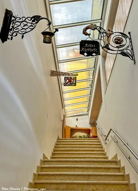 Escadaria interior do Museu da Farmácia em Lisboa com tabuletas antigas de farmácia em ferro forjado