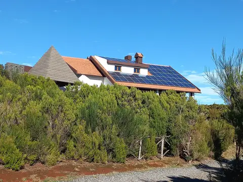 Edifício com telhado de colmo e painéis solares na Achada do Teixeira, rodeado de vegetação de montanha
