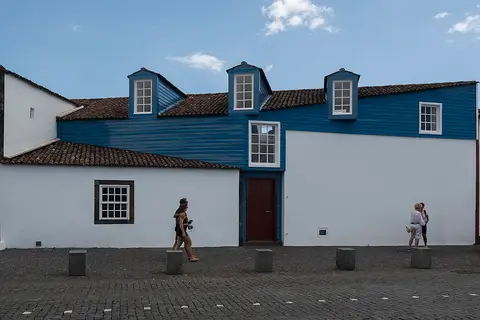 Fachada branca e azul do Museu dos Baleeiros, na Ilha do Pico, com janelas e porta de madeira.
