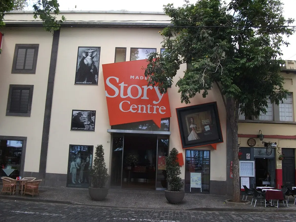Fachada do Madeira Story Centre no Funchal, com letreiro laranja sobre a entrada e esplanada ao lado