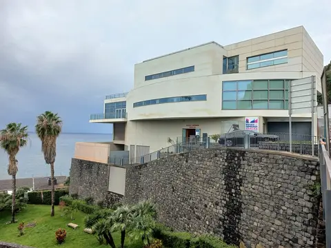 Edifício moderno do Museu da Imprensa da Madeira sobre muro de pedra, junto ao mar