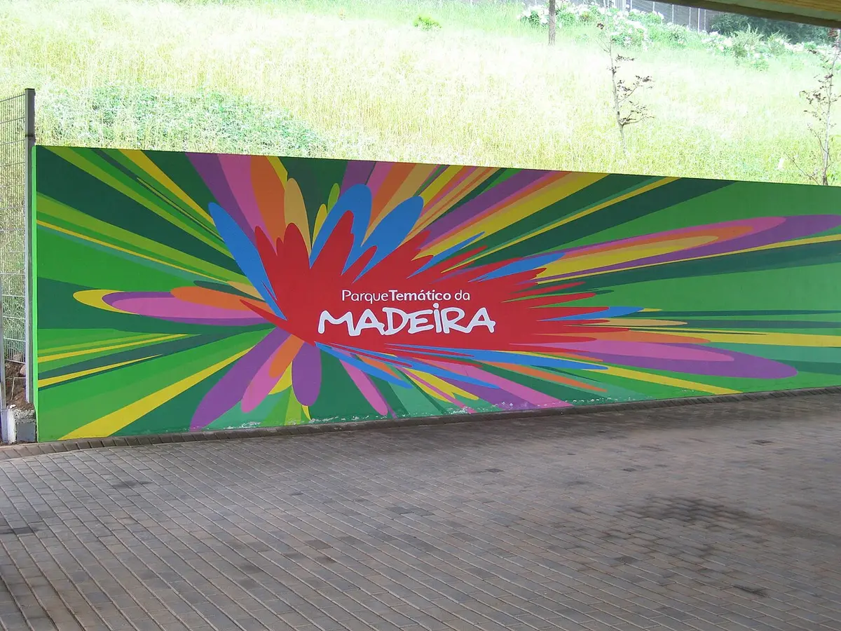 Painel colorido com o letreiro do Parque Temático da Madeira junto a pavimento em calçada