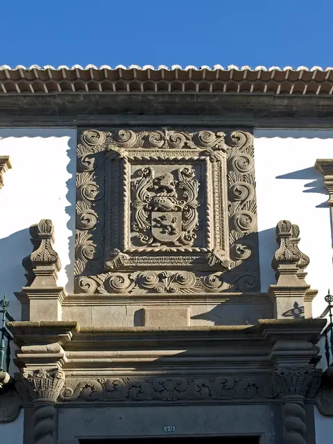 Pormenor da fachada do Palácio Bettencourt com brasão esculpido em pedra sobre o portal