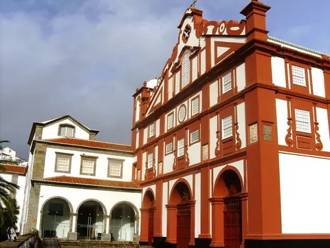 Fachada vermelha e branca do Museu de Angra do Heroísmo, nos Açores, com arcadas e frontão barroco