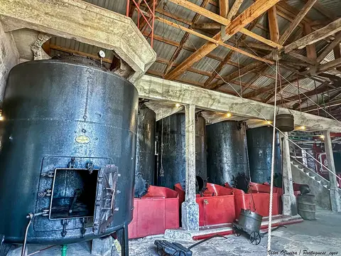 Interior do Museu da Indústria Baleeira, com grandes caldeiras metálicas e tanques vermelhos