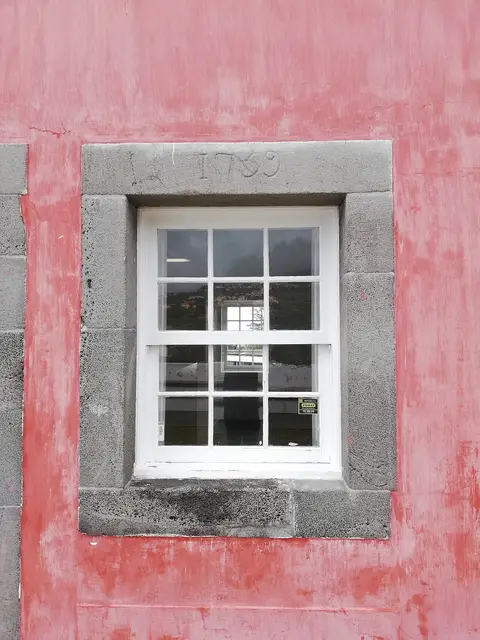 Janela de guilhotina com moldura de pedra e data de 1739 em fachada rosa da Casa das Mudas