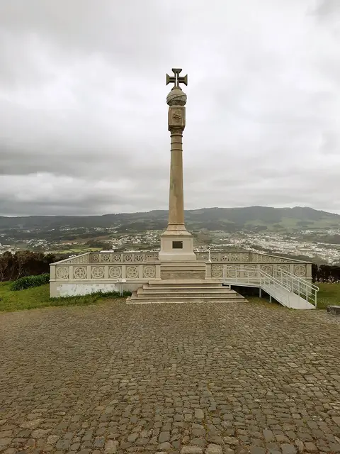 Monumento com cruz no Miradouro do Pico das Cruzinhas, com vista sobre a ilha e o mar ao fundo
