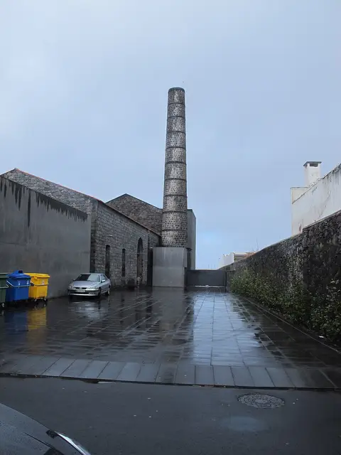 Exterior do Arquipélago - Centro de Artes Contemporâneas, com a chaminé de pedra e o pátio molhado pela chuva