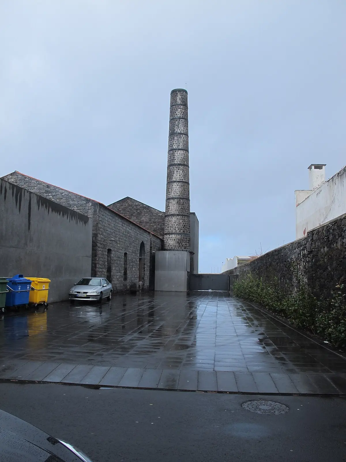 Exterior do Arquipélago - Centro de Artes Contemporâneas, com a chaminé de pedra e o pátio molhado pela chuva