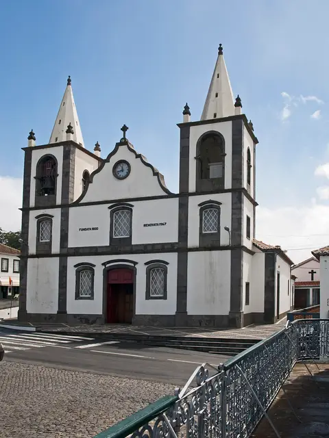 Igreja branca com duas torres e relógio na fachada, em São Bartolomeu dos Regatos