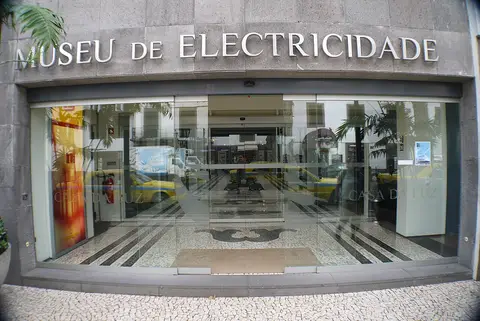 Entrada envidraçada do Museu de Electricidade — Casa da Luz, com letreiro na fachada de pedra