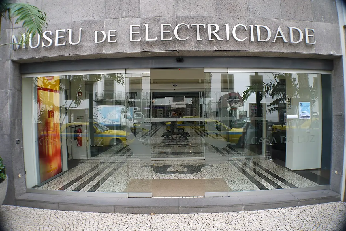 Entrada envidraçada do Museu de Electricidade — Casa da Luz, com letreiro na fachada de pedra