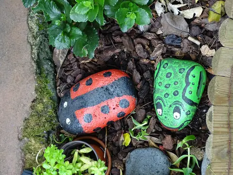 Calhaus pintados como joaninha e sapo num canteiro da Quinta Pedagógica dos Prazeres