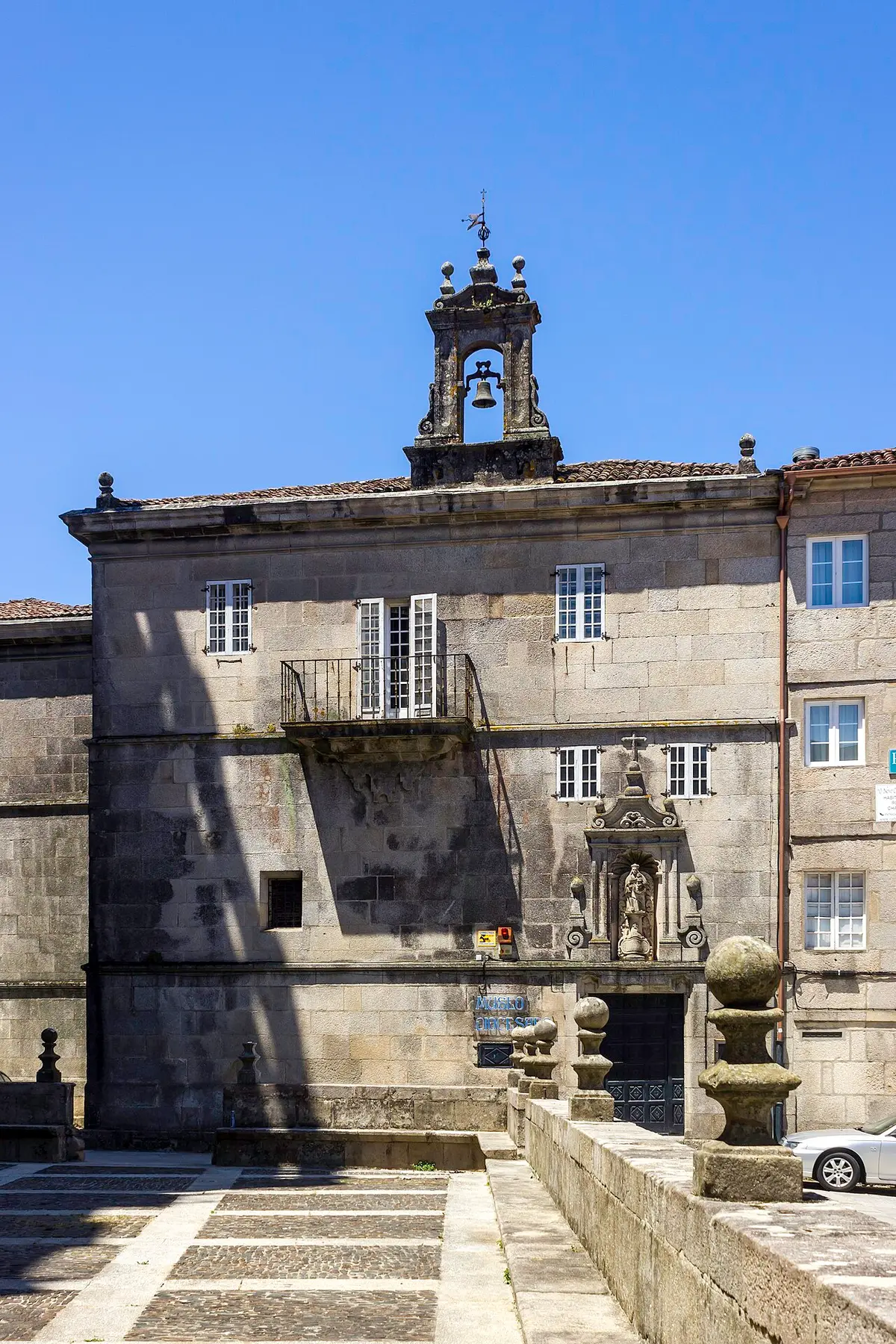 Fachada em pedra do Museu Diocesano de Tui, com campanário e varanda, sob céu azul