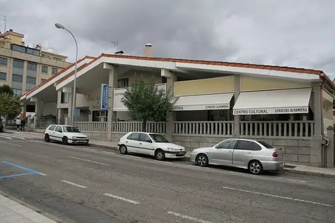 Edifício da casa da cultura e biblioteca municipal, com cafetaria e carros estacionados na rua