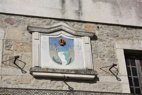 Brasão heráldico pintado na fachada de pedra de um edifício histórico