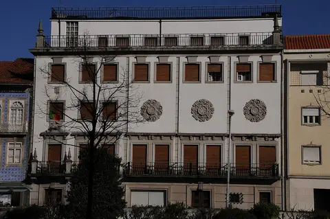 Fachada branca do Museu Nogueira da Silva, em Braga, com rosáceas em relevo e bandeira portuguesa