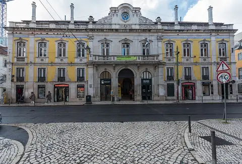 Fachada amarela e branca do edifício da Biblioteca Camões, em Lisboa, vista da rua