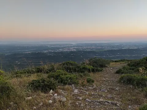 Vista panorâmica ao entardecer do alto do Formosinho, com vegetação rasteira e rochas em primeiro plano