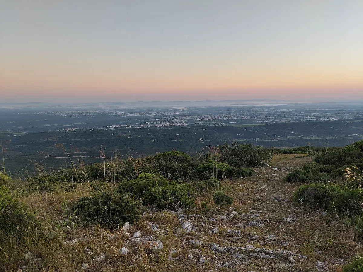 Vista panorâmica ao entardecer do alto do Formosinho, com vegetação rasteira e rochas em primeiro plano