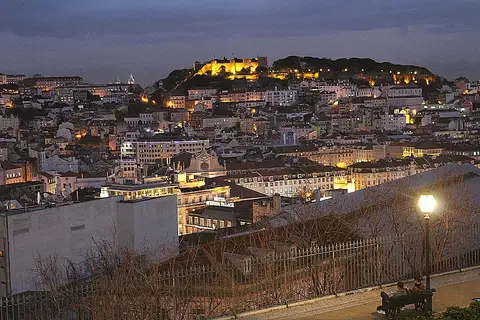 Vista noturna de Lisboa a partir do Miradouro de São Pedro de Alcântara, com o castelo iluminado ao fundo