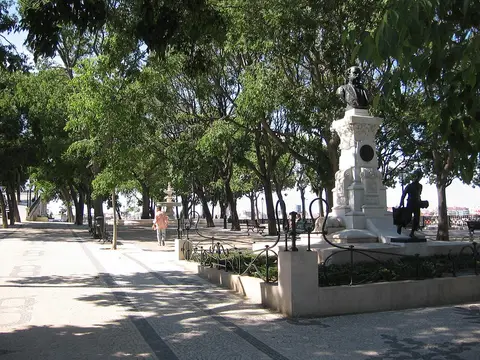 Jardim do Miradouro de São Pedro de Alcântara com árvores, calçada portuguesa e monumento em pedra