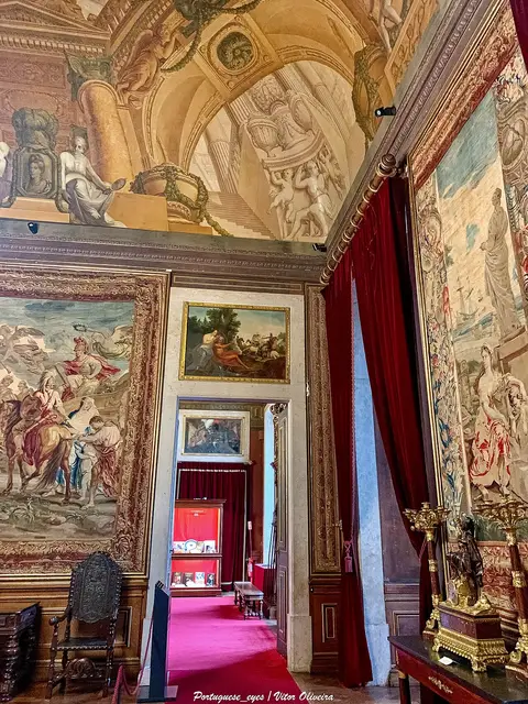 Sala do Palácio Nacional da Ajuda com tapeçarias, tectos pintados e cortinados vermelhos