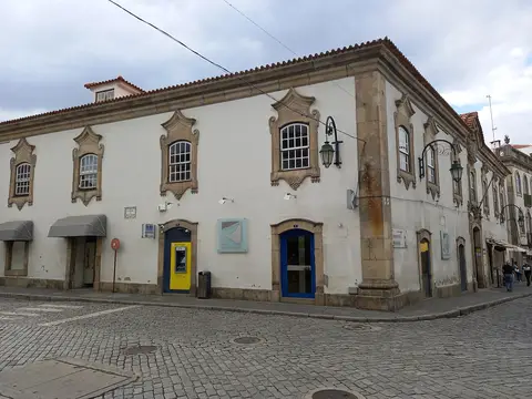 Edifício histórico branco com janelas de cantaria, sede da biblioteca municipal, numa esquina calcetada