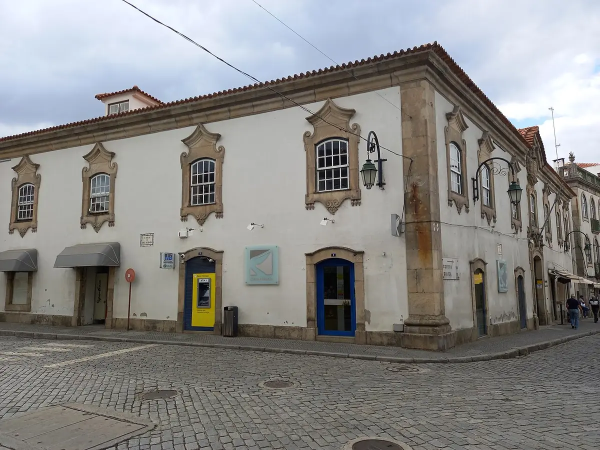 Edifício histórico branco com janelas de cantaria, sede da biblioteca municipal, numa esquina calcetada