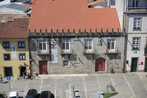 Fachada em granito da Biblioteca Municipal de Barcelos, com varandas e telhado vermelho, vista do alto.