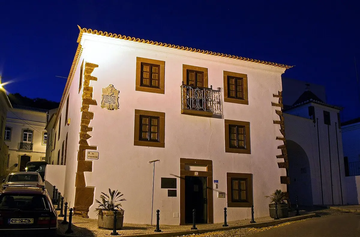Fachada branca da Casa-Museu João de Deus iluminada ao anoitecer, em São Bartolomeu de Messines
