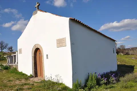 Capela branca com cruz de pedra no castro de São João das Arribas, sob céu azul