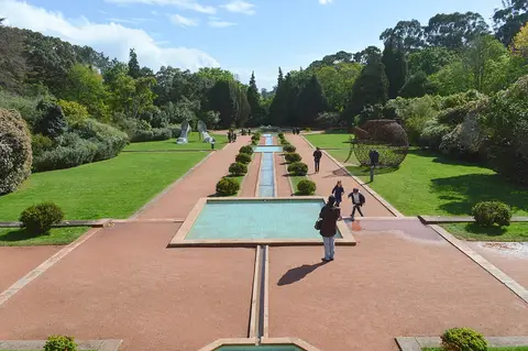 Jardins de Serralves com espelho de água central, sebes aparadas e visitantes ao longe