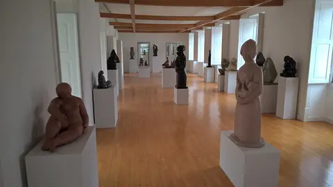 Sala de exposição do Museu Municipal do Bombarral com esculturas sobre plintos brancos e chão de madeira.