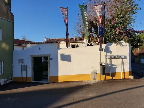 Entrada da Casa-Museu Leal da Câmara, muro branco e amarelo com bandeiras e placa indicativa