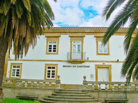 Fachada branca do Museu do Canteiro, com cantarias em pedra, varanda de ferro e escadaria, entre palmeiras.