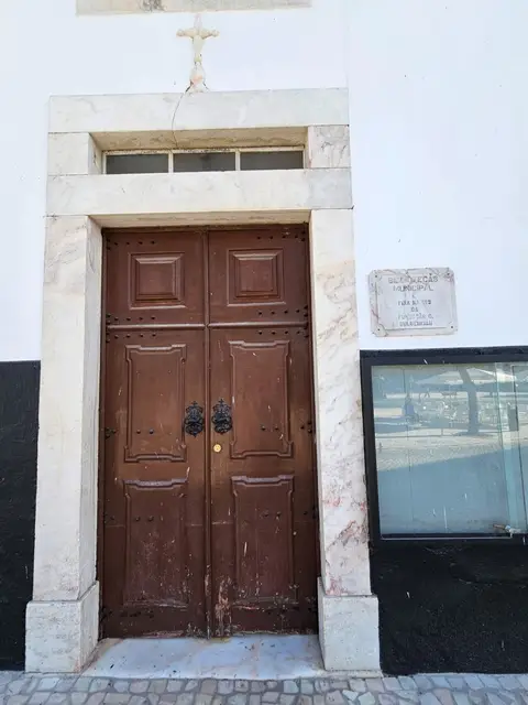 Porta de madeira com moldura de mármore e placa da antiga Biblioteca Municipal de Estremoz
